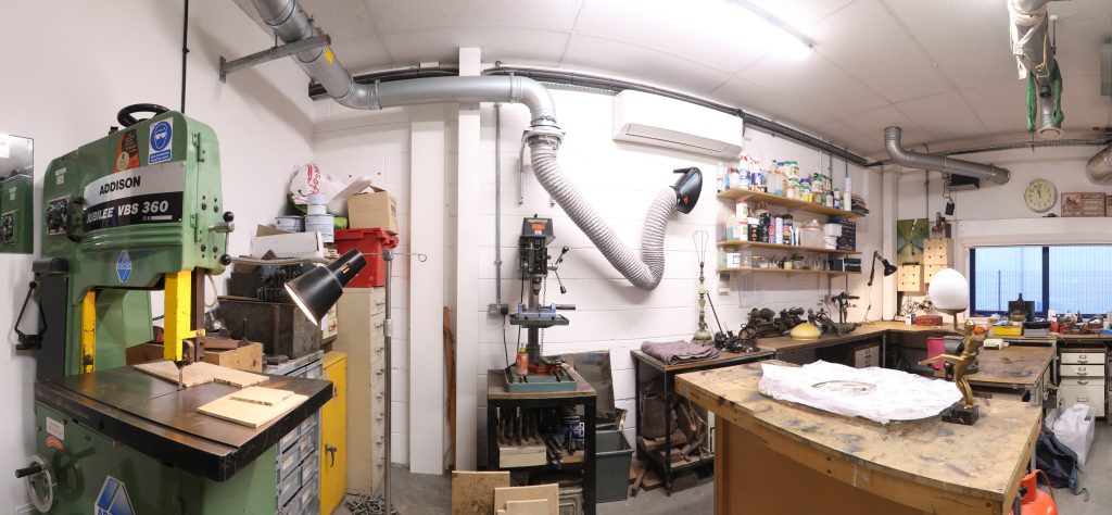 Panoramic view of the Plowden & Smith metals workshop interior showing a bandsaw, pillar drill, workbenches and extraction.